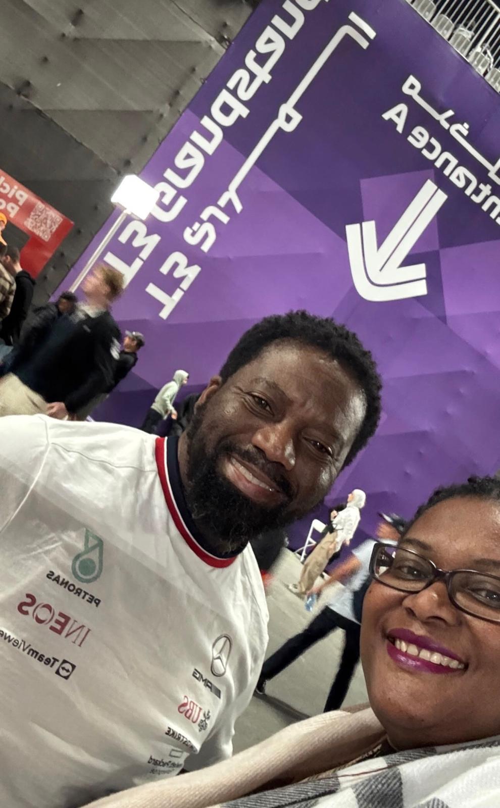 Malcolm wearing a Mercedes team shirt beside a companion at a Formula One venue