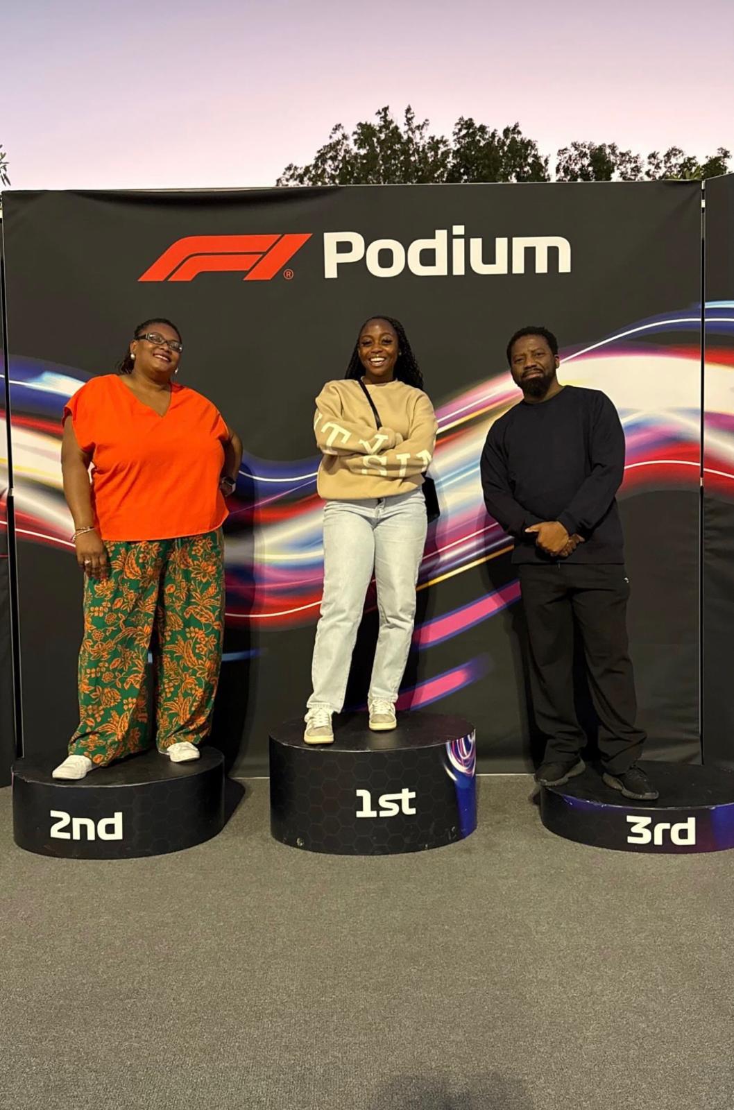 Malcolm and companions posing on an F1 podium display